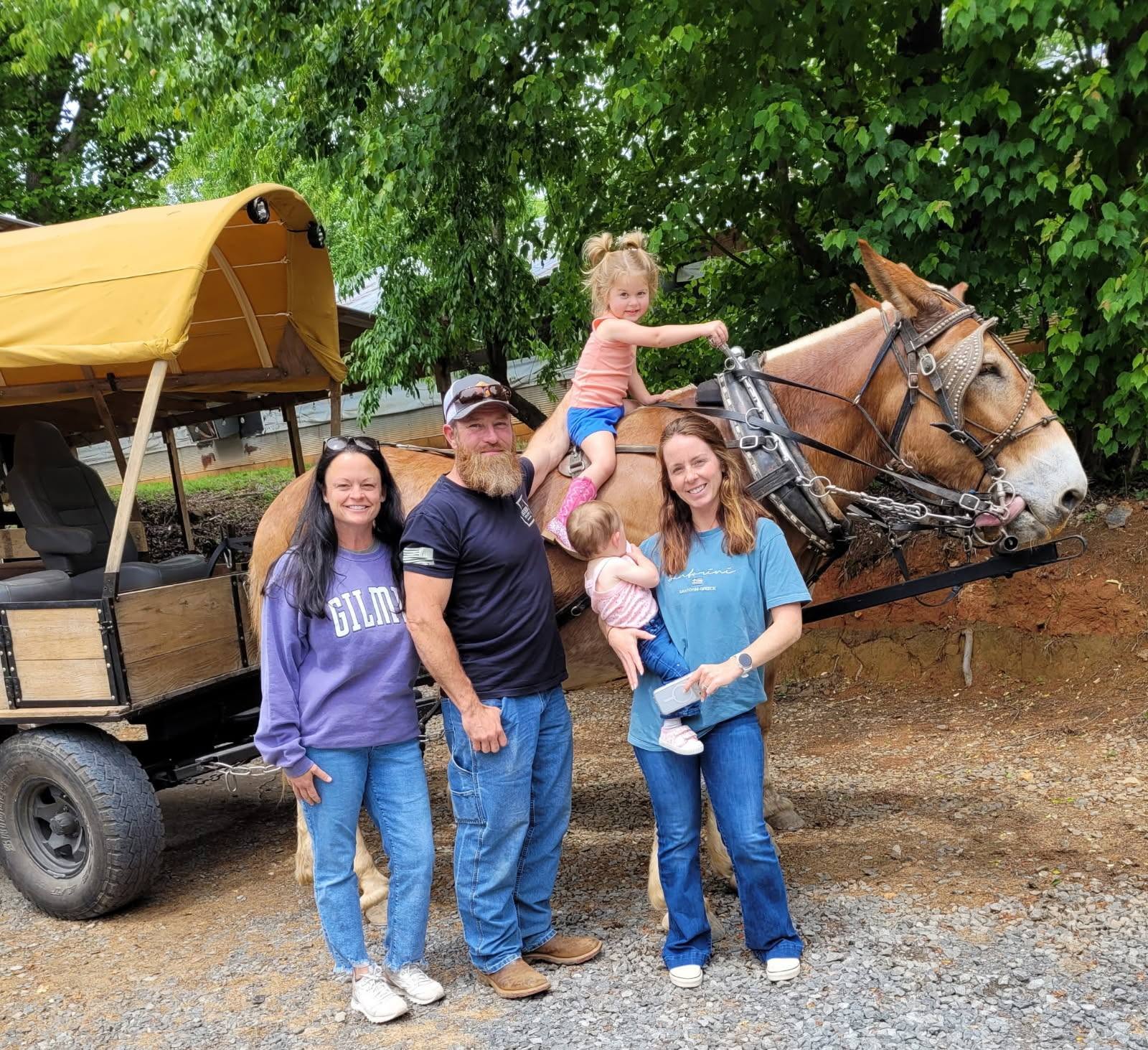 A family posing with one of the mules in front of the canopy wagon